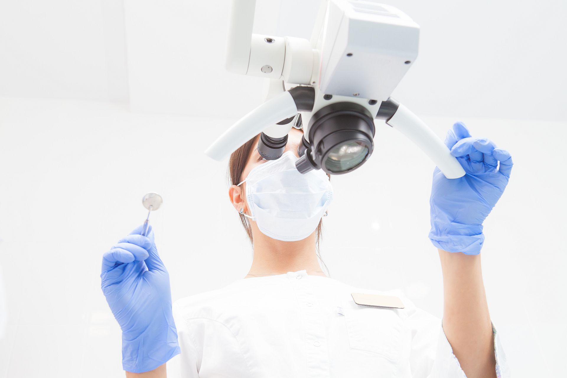 A female dentist is looking into a dental microscope. Bottom view. Focus on the doctor
